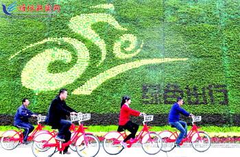 市民騎公共自行車路過市人民廣場一處花壇。記者 張馳